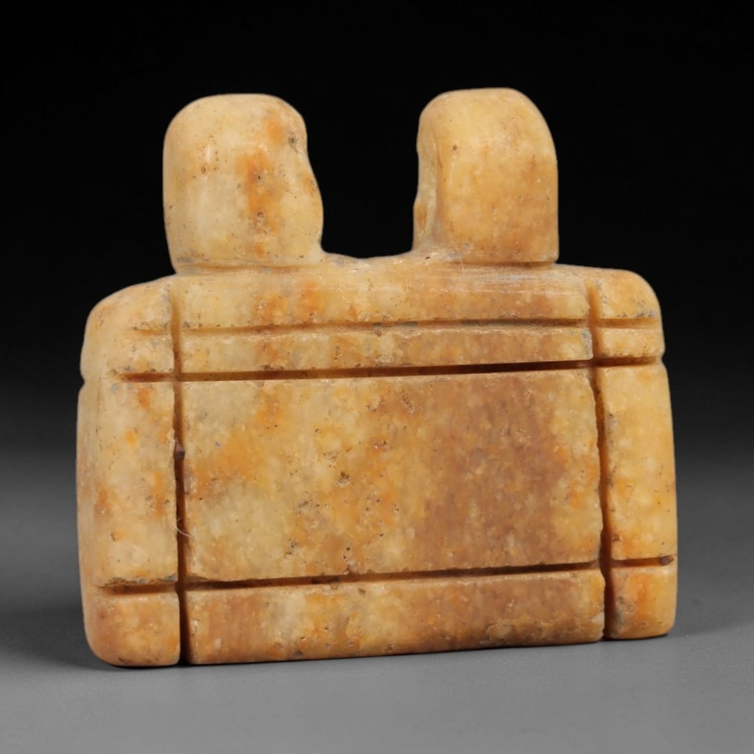 Ancient Egyptian Stone Amulet - Geometric Carved Pendant, 17AE: Carved from light-toned stone, this ancient Egyptian amulet features a rectangular form with two humanoid heads at the top and incised geometric detailing along its length, a motif typical of Egyptian