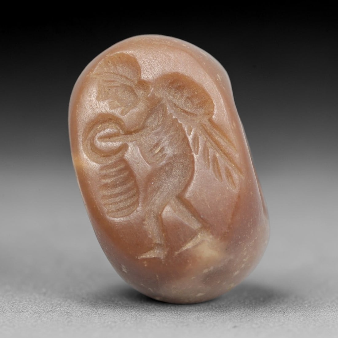Ancient Stone Hemispherical Stamp Seal - Near Eastern Winged Figure, 52ZS: Crafted from dense, light brown stone, this hemispherical stamp seal bears incised carving of a winged anthropomorphic figure, depicted with a helmet, outstretched wings, and holding a coiled object a