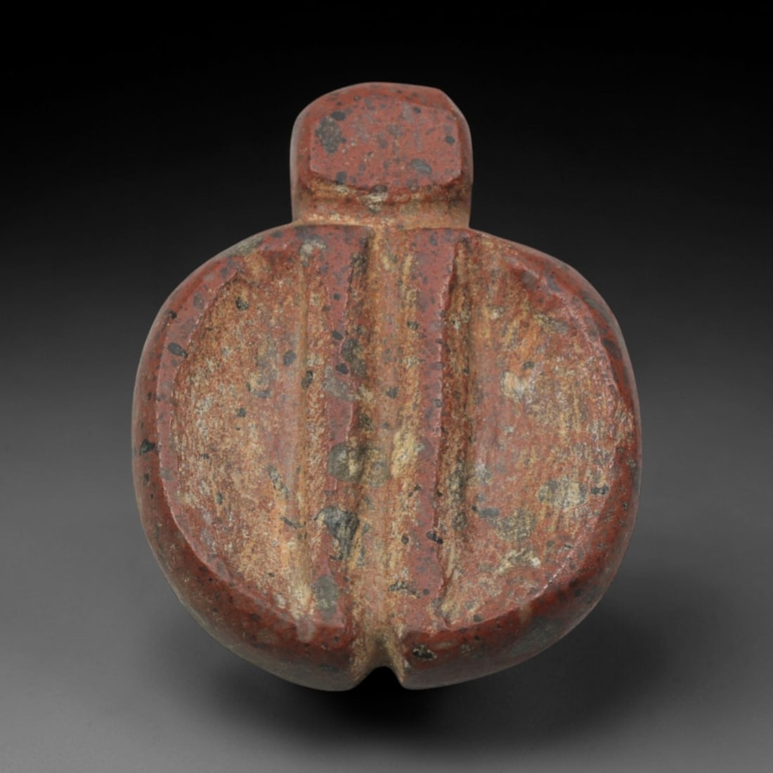 Ancient Red Stone Scaraboid Pendant - Near Eastern Ritual Amulet, 10XQ: Carved from a speckled, deep red stone with natural grey and black mineral inclusions, this miniature pendant takes the stylized form of a scaraboid (beetle-like) motif, a powerful symbol of protectio