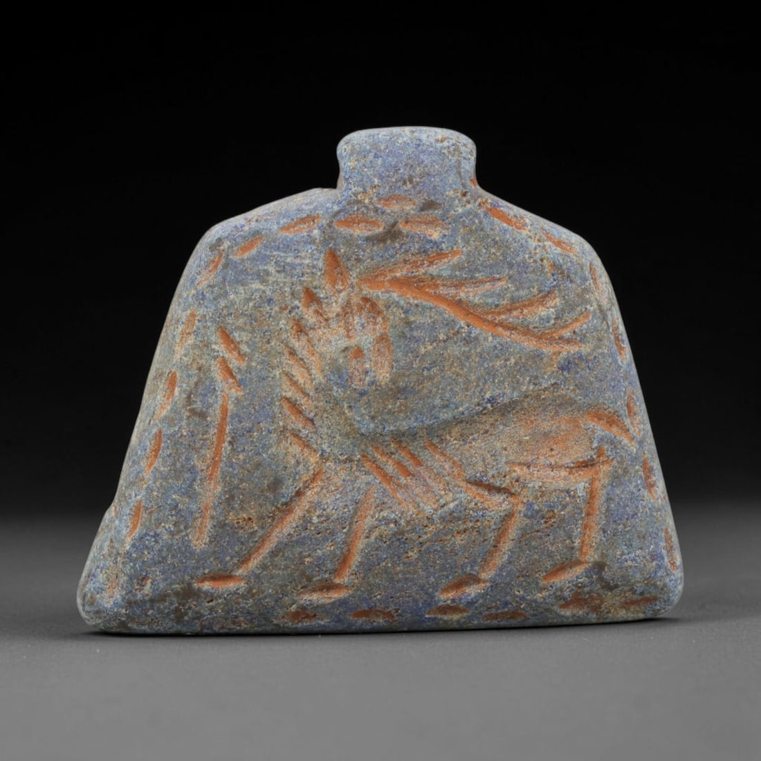 Ancient Lapis Lazuli Amulet - Near Eastern Stag Figurine, 3ZX: Carved from lapis lazuli, the amulet is a flattened, trapezoidal plaque with a raised suspension lug at the top, crafted in the ancient Near Eastern style. The front surface is incised with a stylized