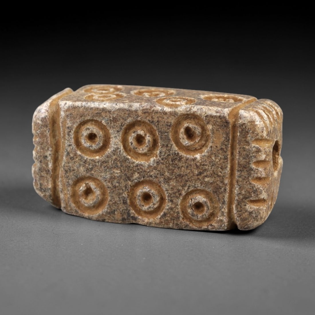 Ancient Steatite Amulet - Near Eastern Concentric Circles, 43AK: Crafted from steatite, this rectangular amulet features incised concentric circle motifs arranged in a 2x3 grid across its primary face, with decorative linear carvings framing the suspension hole on