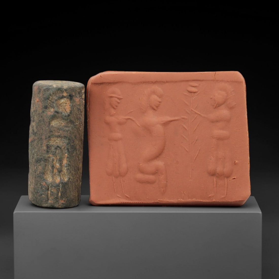 Ancient Near Eastern Stone Cylinder Seal - Human & Floral Motif, 70AH: Carved from fine-grained stone, this cylinder seal features incised depictions of human figures alongside floral elements, a motif characteristic of ancient Near Eastern glyptic art. The piece exhibit
