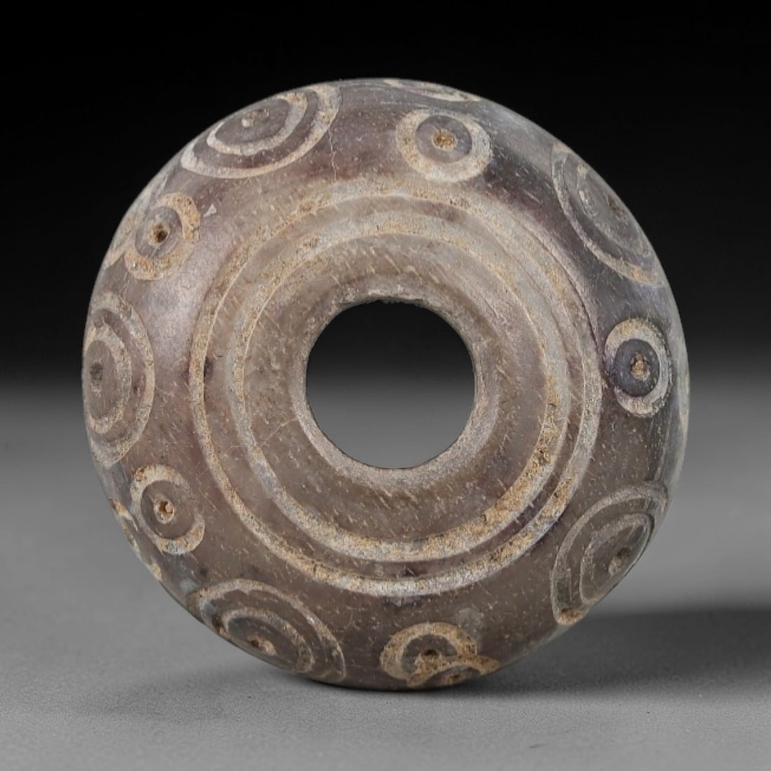 Ancient Near Eastern Bone Spindle Whorl - Dot-in-Circle Motif, 84AH: Carved from ancient bone, this Near Eastern spindle whorl features a continuous dot-in-circle motif encircling its central perforation, a design with apotropaic significance in ancient Near Eastern cu
