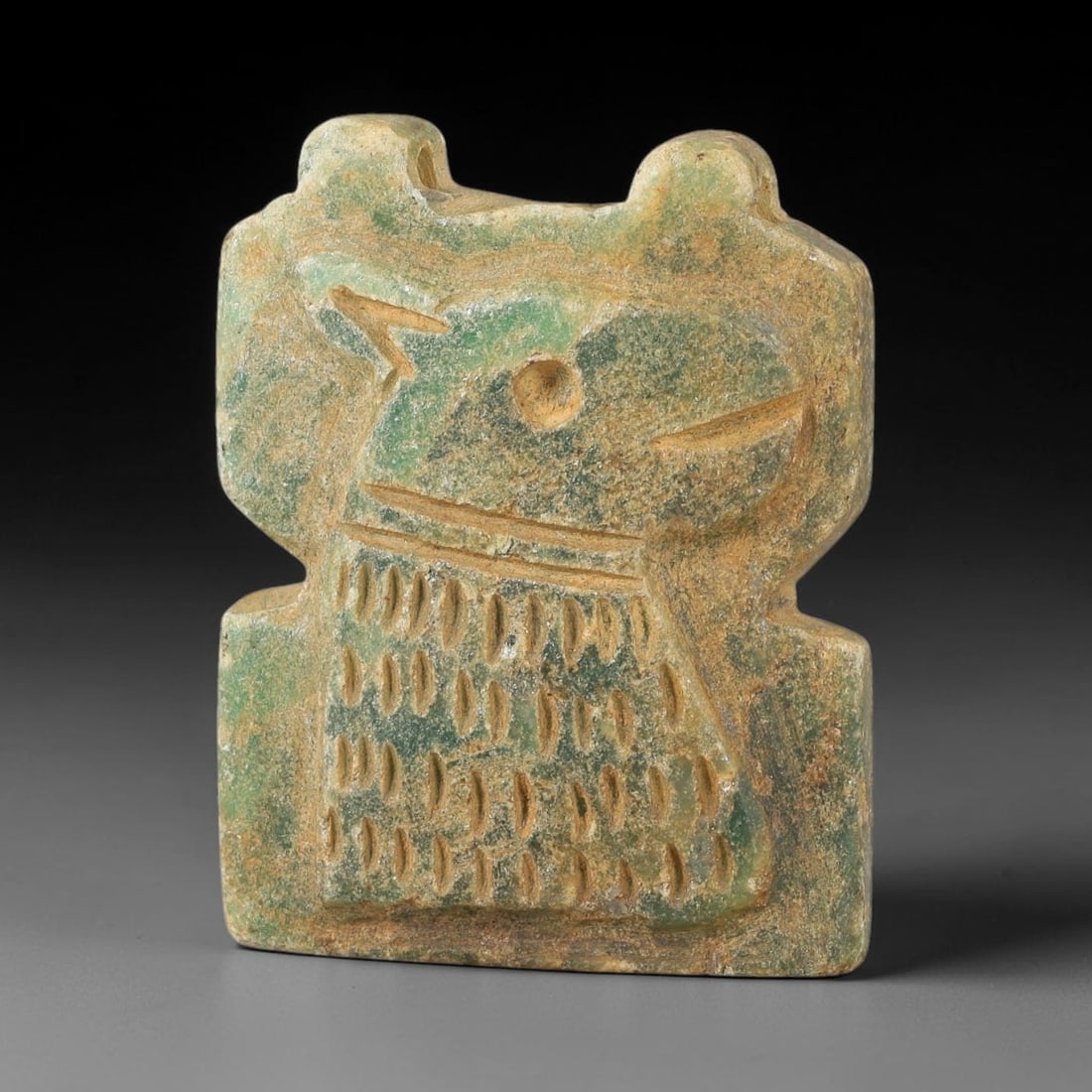 Ancient Serpentine Amulet - Near Eastern Carved Figurine, 5BA: Carved from serpentine, the amulet takes the form of a stylized zoomorphic or anthropomorphic figure, rendered in flat relief with incised decorative detail. A central circular perforation serves as a