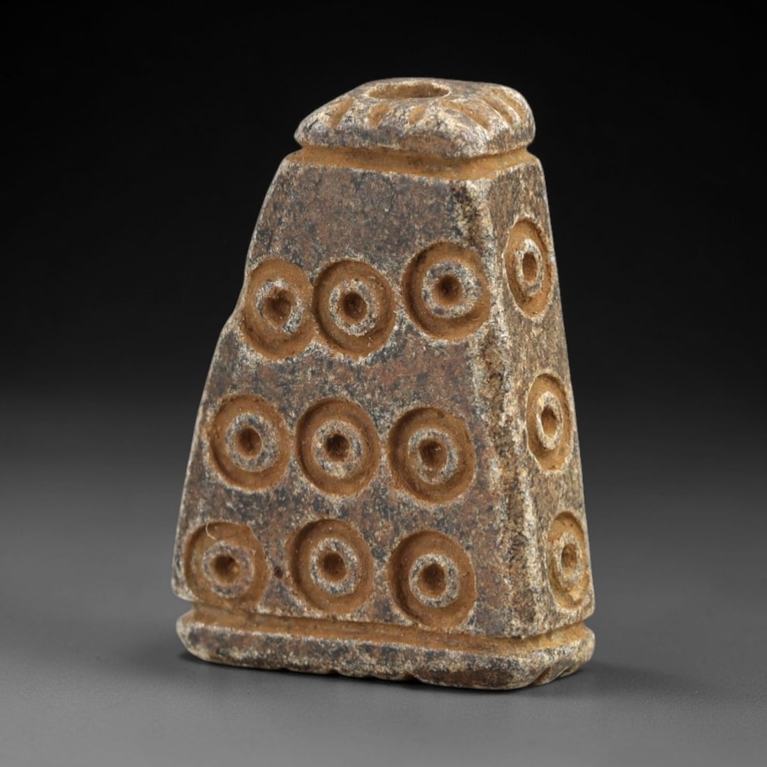 Ancient Steatite Amulet - Near Eastern Concentric Circles, 34AK: Crafted from steatite, this tapering conical amulet features deeply incised concentric circle motifs arranged in horizontal rows across its body, with a pronounced suspension hole piercing the flatten