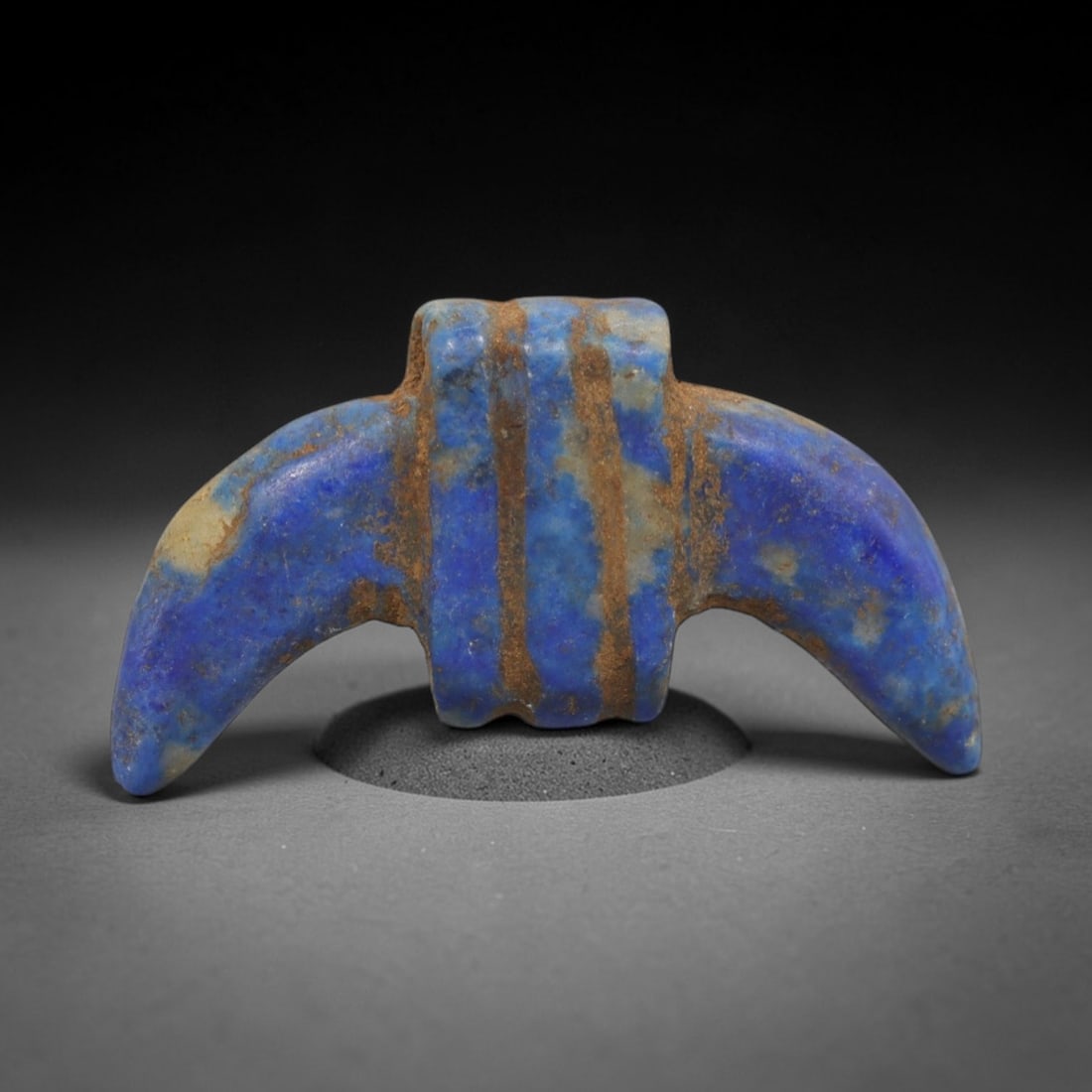 Ancient Lapis Lazuli Amulet - Egyptian Crescent Pendant, 33ZT: Carved from lapis lazuli, this amulet features a symmetrical double-crescent form with a rectangular central block pierced for suspension, its surface incised with vertical bands that define its segme