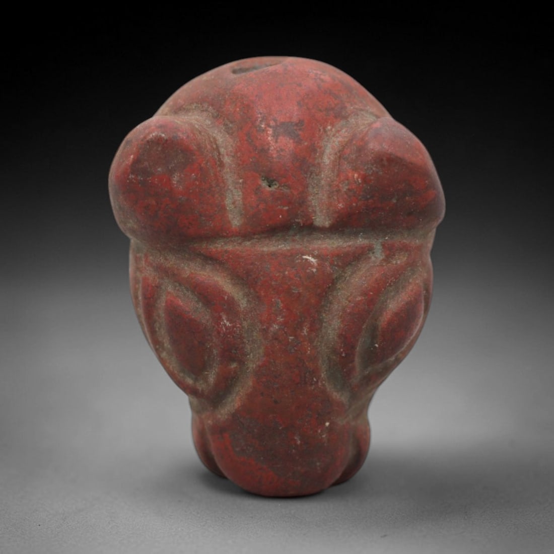 Ancient Near Eastern Red Stone Ram Head Amulet - Carved Pendant Figure, 45ZV: This amulet is carved from a rich, variegated red stone with natural mineral speckling, likely brecciated jasper or red steatite, featuring a stylized ram head form. The piece displays prominent, roun