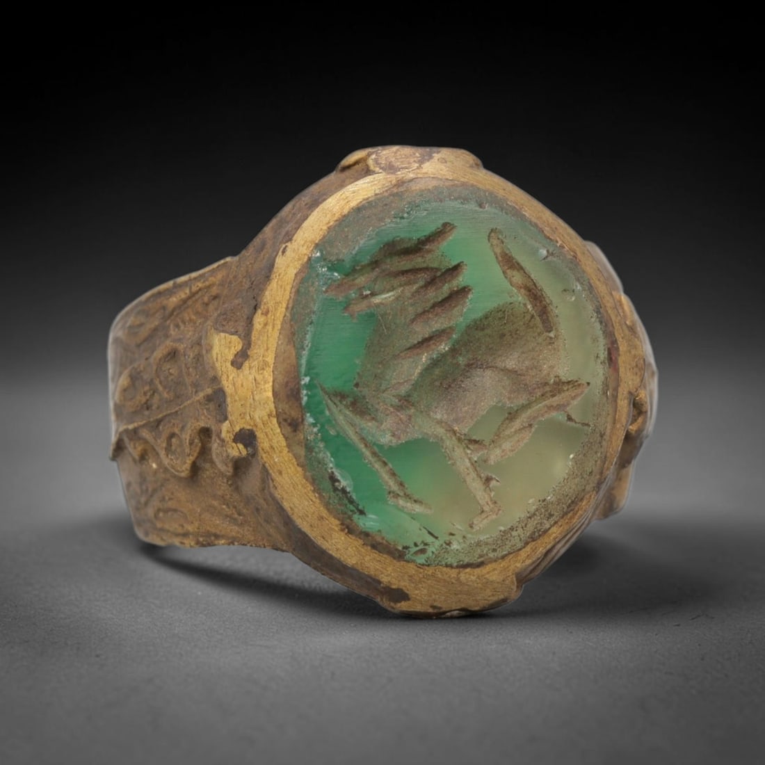 Antique Qajar Dynasty Green Intaglio Ring - Size 9 US, 95ZX: Crafted from gilt brass with a rounded bezel, this ring features a carved green intaglio stone at its center, incised with a stylized equine motif characteristic of Qajar-era Persian symbolic carving.