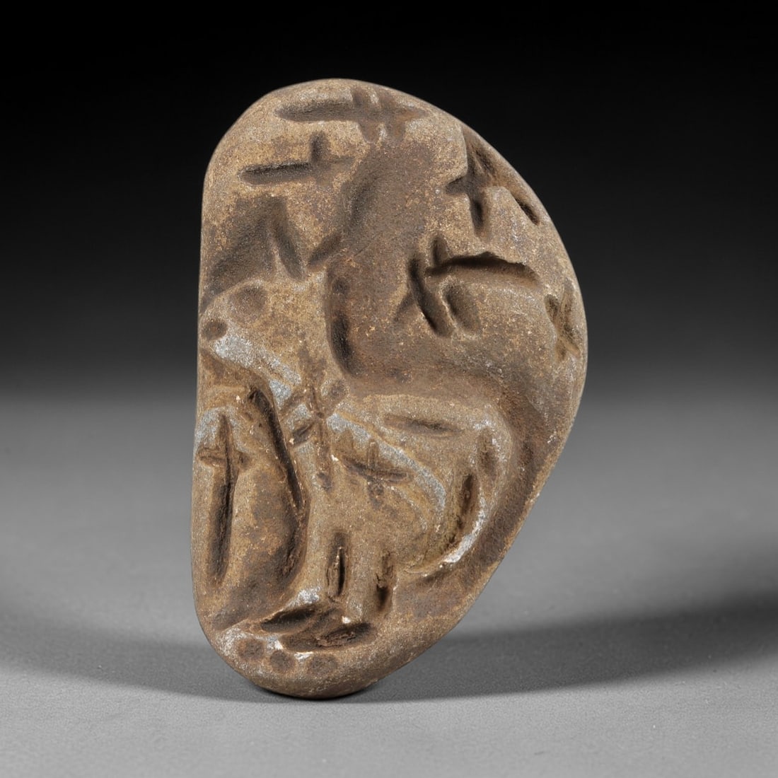Ancient Stone Zoomorphic Amulet - Near Eastern Christian Figurine, 6FY: Carved from a naturally smoothed stone pebble, this piece features a relief depiction of a zoomorphic figure, likely a quadrupedal animal, adorned with incised cross motifs across its body and limbs,