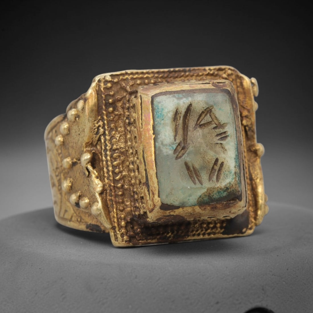 Antique Qajar Dynasty Brass Intaglio Ring - Size 10 US, 7WJ: Crafted from brass with a substantial square bezel, this ring features a carved intaglio stone set at its center, adorned with intricate granulation and beaded detailing around the bezel perimeter and
