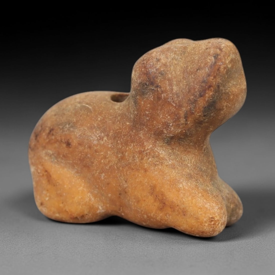 Ancient Tan Stone Recumbent Animal - Near Eastern Amulet, 9AE: Carved from warm tan stone with natural surface patination, this amulet depicts a compact, stylized recumbent animal in a simplified, rounded form. The creature is rendered in a prone posture, with mi