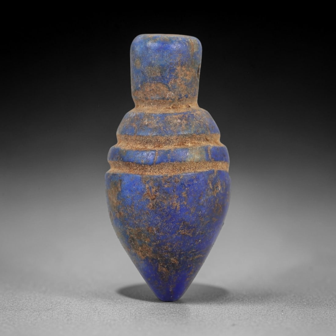 Ancient Lapis Lazuli Heart Amulet - Egyptian Ritual Pendant, 10AP: Carved from lapis lazuli, this amulet is formed in the shape of a heart, with a cylindrical upper lug pierced for suspension, its body marked by three incised horizontal bands that define its structur