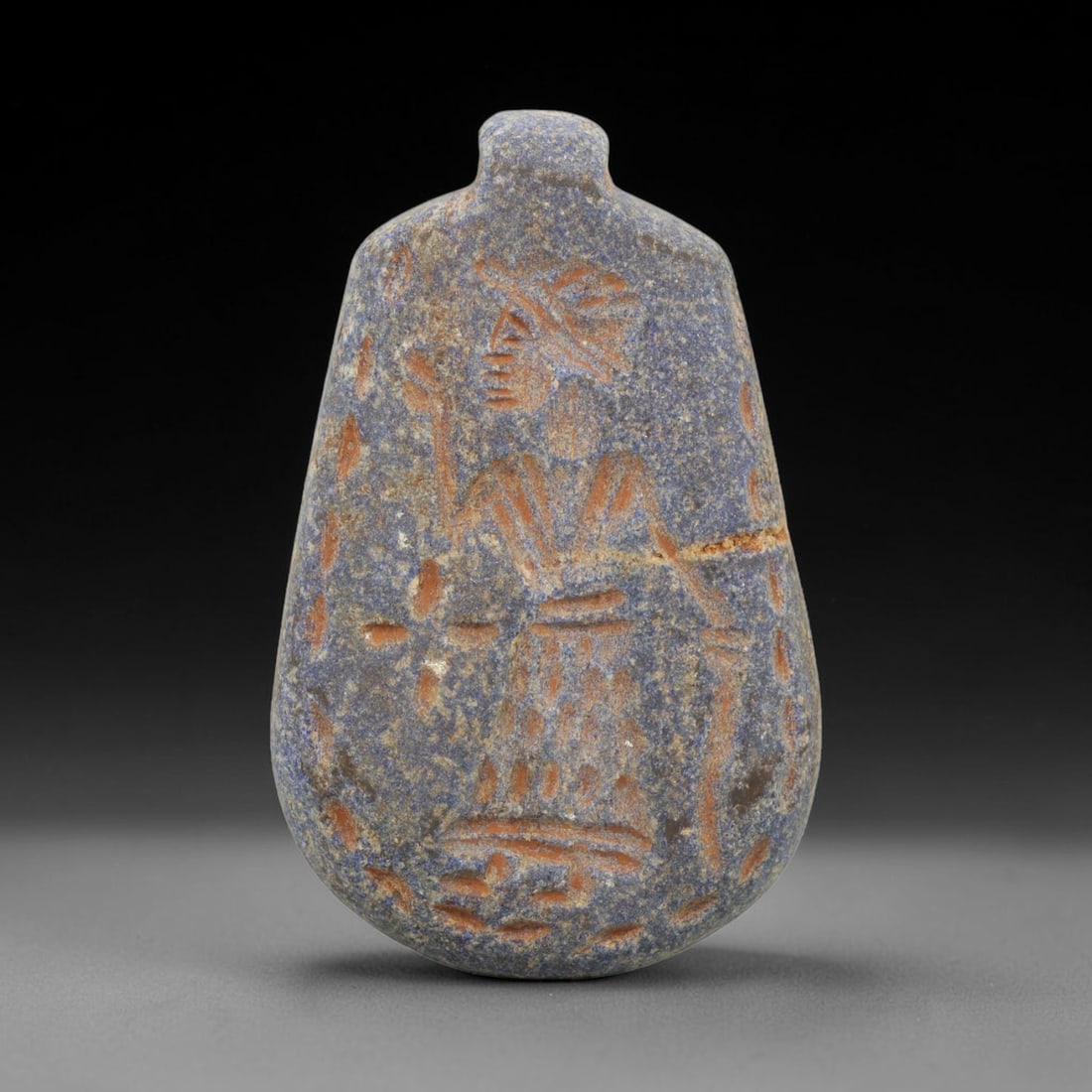 Ancient Lapis Lazuli Amulet - Near Eastern Human Figure, 96ZT: Carved from lapis lazuli, this amulet features a relief depiction of a standing human figure, rendered in the stylized glyptic tradition of the ancient Near East. The figure is detailed with incised l