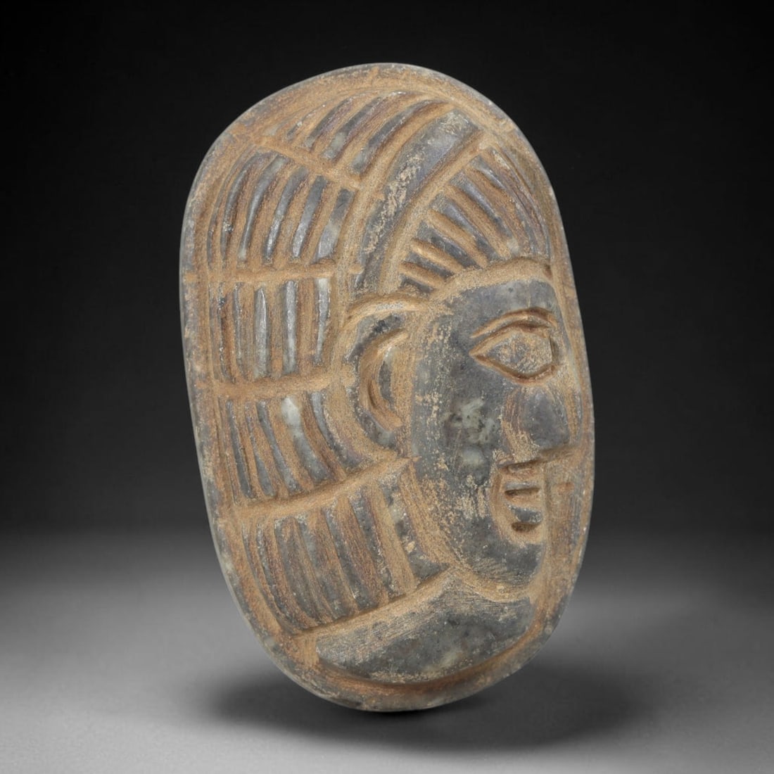 Ancient Stone Amulet - Near Eastern Bust Plaque Pendant, 40FY: Carved from dark stone, the amulet is an oval plaque crafted in the ancient Near Eastern style, featuring a raised relief portrait of a human bust in profile. The surface bears incised details renderi