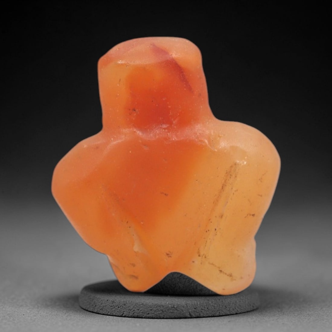 Ancient Agate Bird - Near Eastern Figurine Amulet, 96XS: This amulet is carved from smooth orange agate, displaying natural banding and warm translucency typical of ancient Near Eastern glyptic craftsmanship. The form is a stylized avian figure, with simpli
