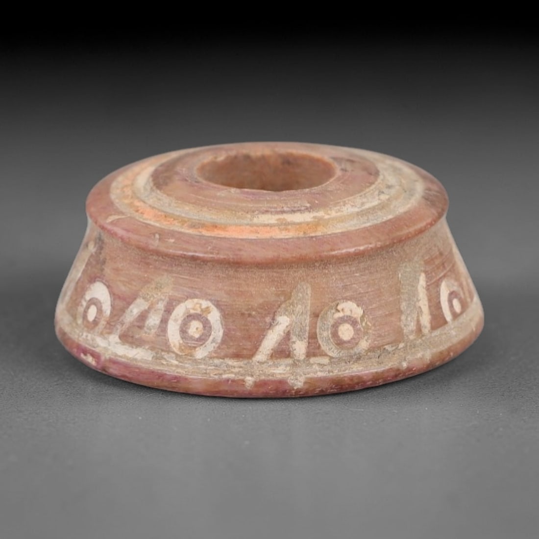Ancient Bone Spindle Whorl - Near Eastern Radiating Motif, 74XR: This ancient Near Eastern spindle whorl is crafted from bone, featuring a convex form with a central perforation. The surface is incised with radiating linear and circular motifs, a decorative techniq