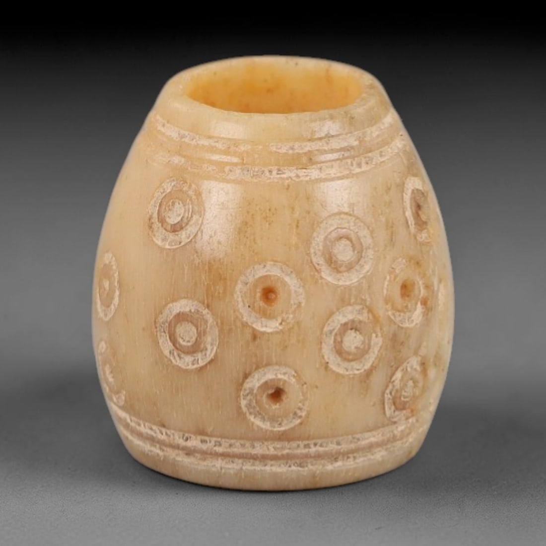 Ancient Bone Spindle Whorl - Near Eastern Concentric Dots, 90XR: This ancient Near Eastern spindle whorl is crafted from bone, featuring a convex form with a central perforation. The surface is incised with concentric circular dot motifs, a decorative technique typ