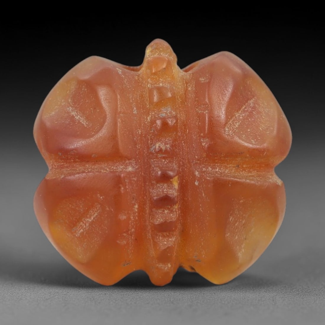 Ancient Carnelian Fly Amulet - Egyptian Figurine, 74AJ: Carved from warm orange carnelian, this amulet is formed as a stylized fly with a segmented central body and four rounded wing cases, consistent with ancient Egyptian protective amulet traditions. A s