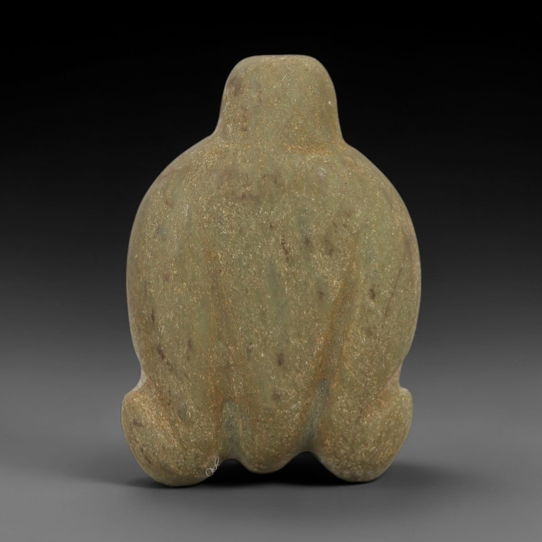 Ancient Stone Frog Amulet - Egyptian Ritual Figurine, 15AG: This amulet is carved from a single piece of pale green stone, with a granular texture and scattered reddish-brown inclusions across its surface. The form is stylized as a frog, with a rounded, compac