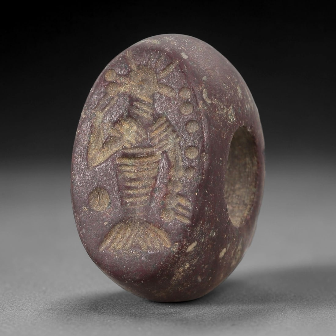 Ancient Stone Hemispherical Stamp Seal - Near Eastern Deity Figure, 94AN: Carved from a dense, dark reddish-brown stone, this hemispherical stamp seal features a flat, oval face incised with a standing anthropomorphic deity figure. The figure is depicted with a radiate head