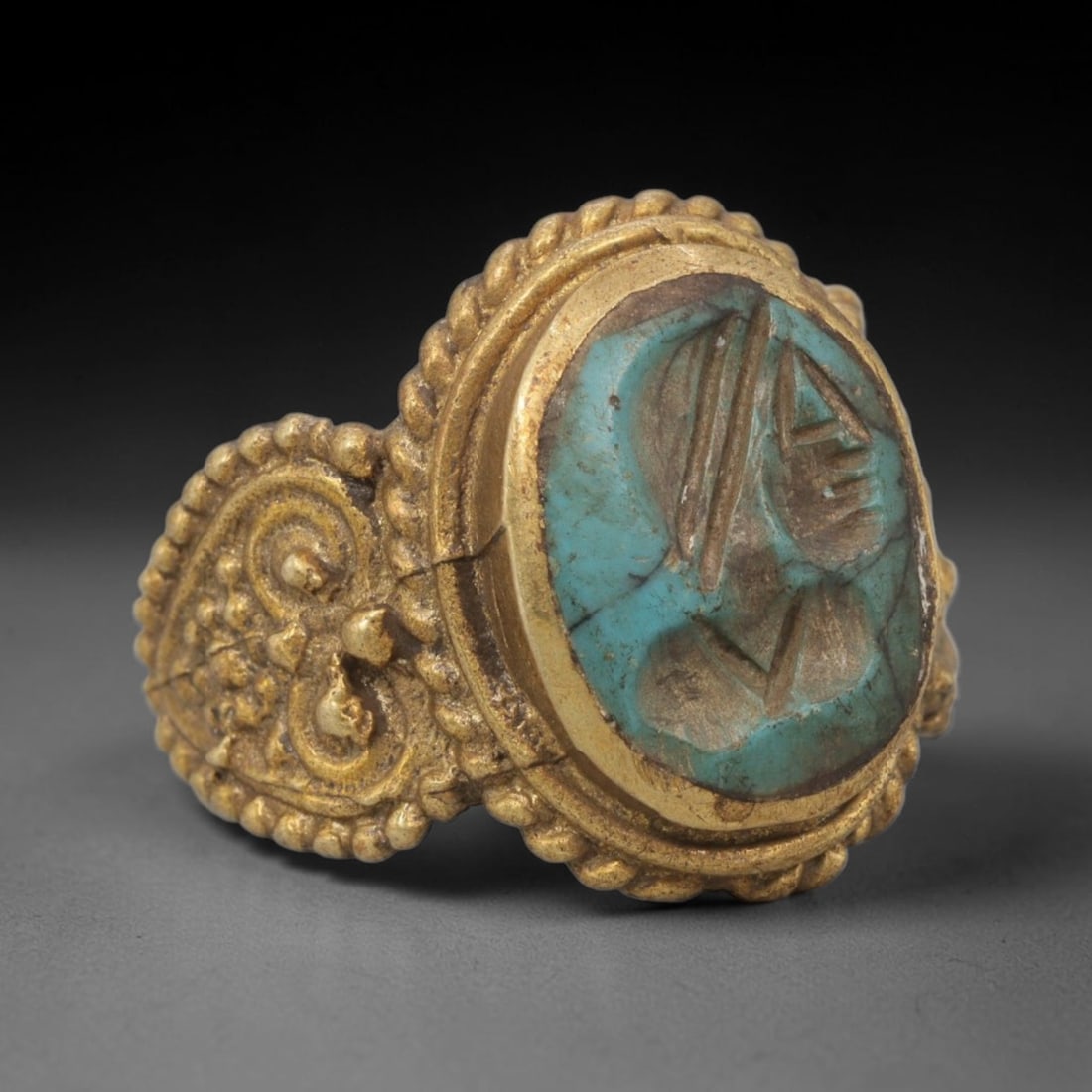Antique Qajar Dynasty Turquoise Intaglio Ring - Size 10 US, 10WJ: Crafted from gilt metal with an ornate oval bezel, this ring features a carved turquoise intaglio stone at its center, depicting an incised profile portrait motif characteristic of Qajar-era Persian s