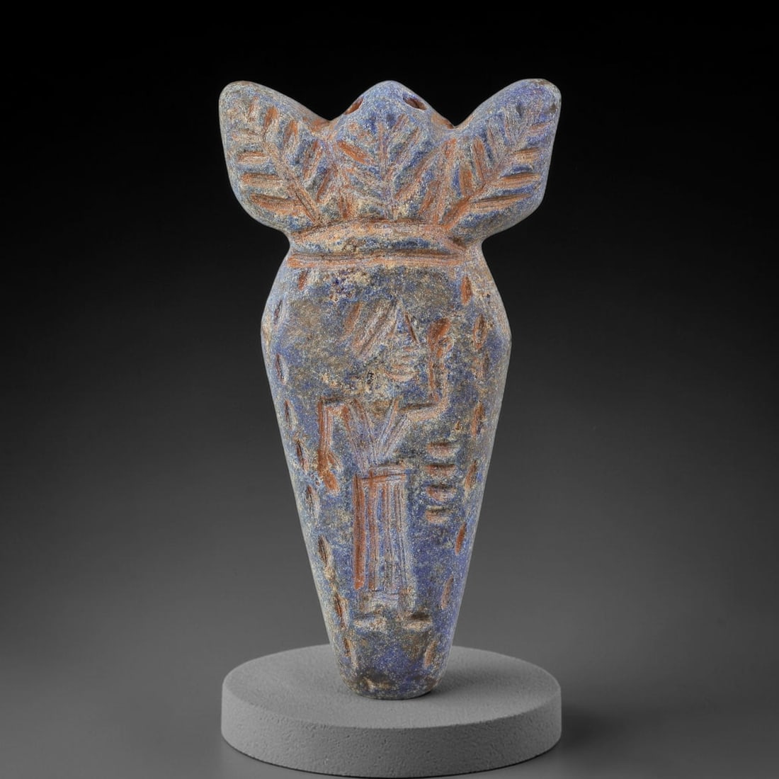 Ancient Lapis Lazuli Amulet - Near Eastern Anthropomorphic Figurine, 8BA: Carved from lapis lazuli, the amulet takes a vase-shaped form with a decorative foliate crown at the top, featuring two drilled suspension holes for wear as a protective talisman. The front face is in