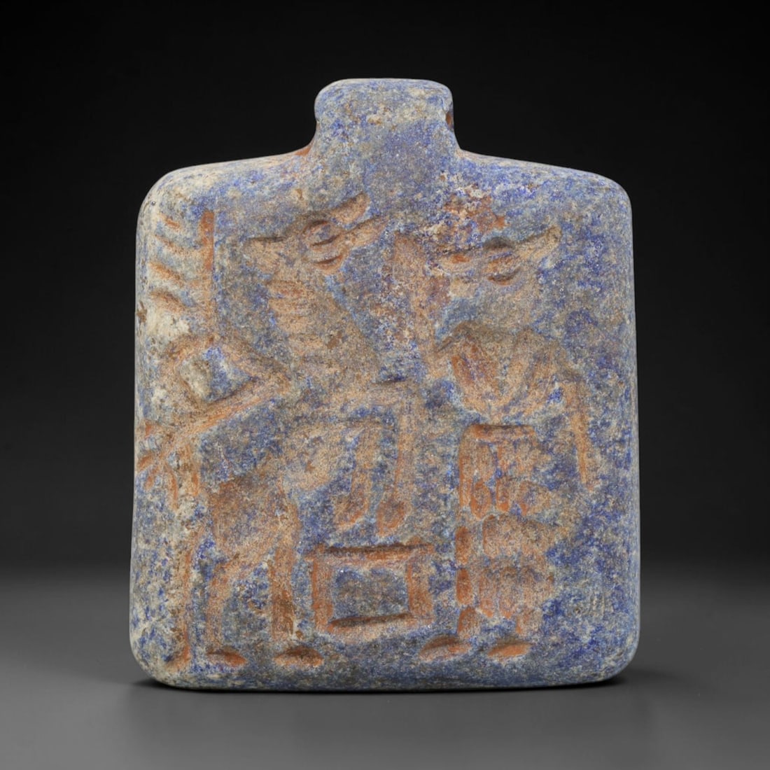 Ancient Lapis Lazuli Amulet - Near Eastern Dual Figure Plaque, 14ZX: Carved from lapis lazuli, this amulet plaque features a relief scene depicting two standing figures in confrontation or dialogue, rendered in the stylized glyptic tradition of the ancient Near East. I