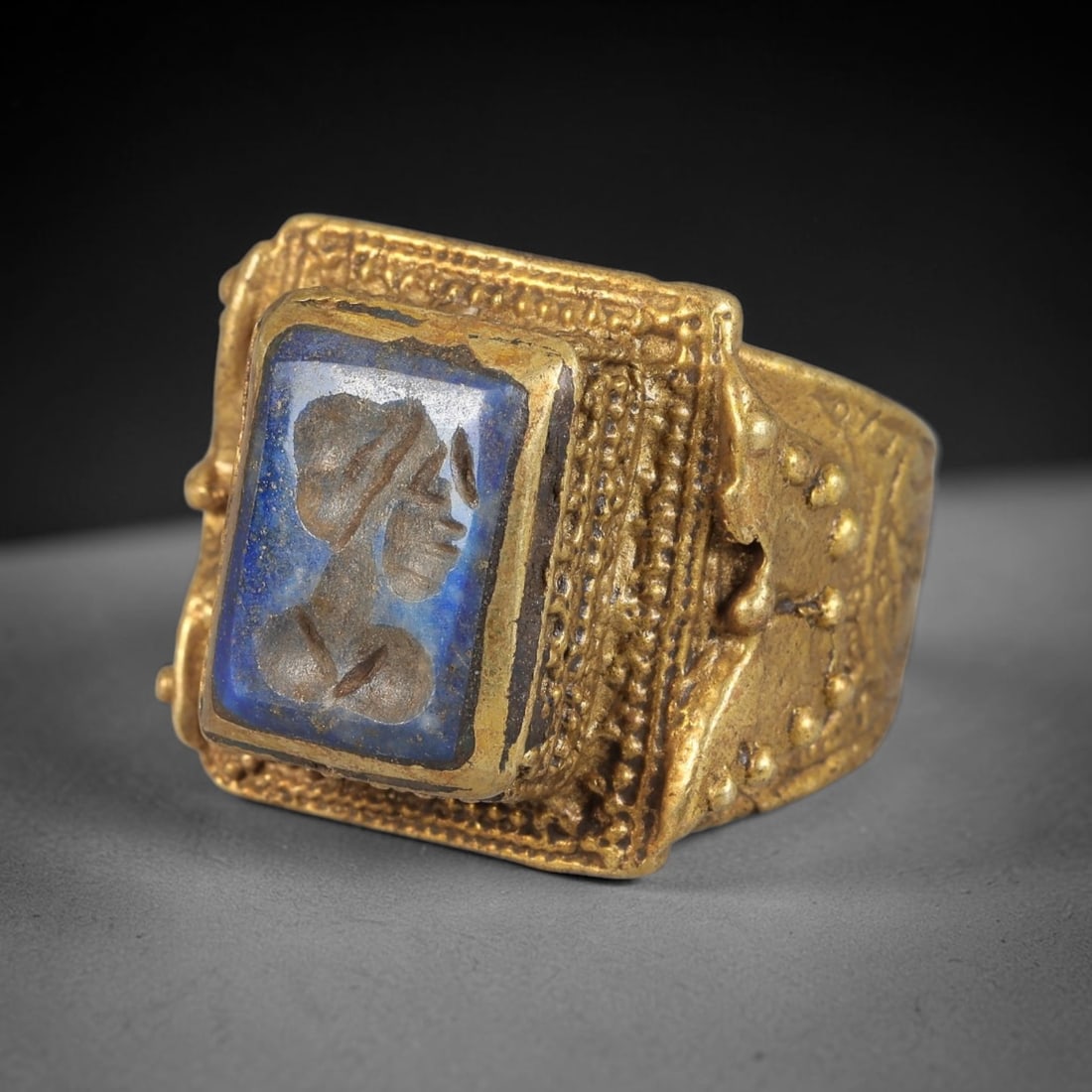 Antique Qajar Dynasty Lapis Lazuli Intaglio Brass Ring - Size 11 US, 77BA: Crafted from brass, this ring features a square-set lapis lazuli intaglio panel carved with a profile figure, executed in the distinctive Qajar style. The brass band exhibits a textured, granular gran