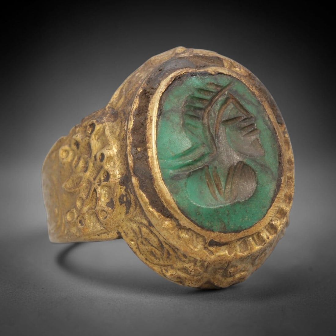 Antique Qajar Dynasty Green Intaglio Ring - Size 8 US, 100ZX: Crafted from gilt brass with a raised oval bezel, this ring features a carved green stone intaglio at its center, depicting an incised profile portrait motif characteristic of Qajar-era Persian symbol