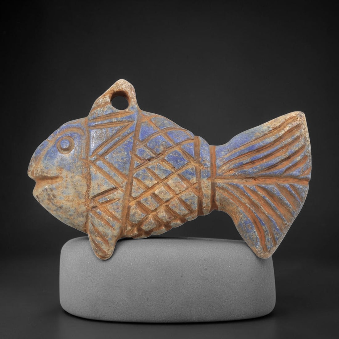 Ancient Lapis Lazuli Fish Amulet - Near Eastern Carving, 51FY: Carved from lapis lazuli, the amulet is shaped in the form of a stylized fish, with a suspension hole drilled through the dorsal fin for wear as a protective talisman. The figure is detailed with inci