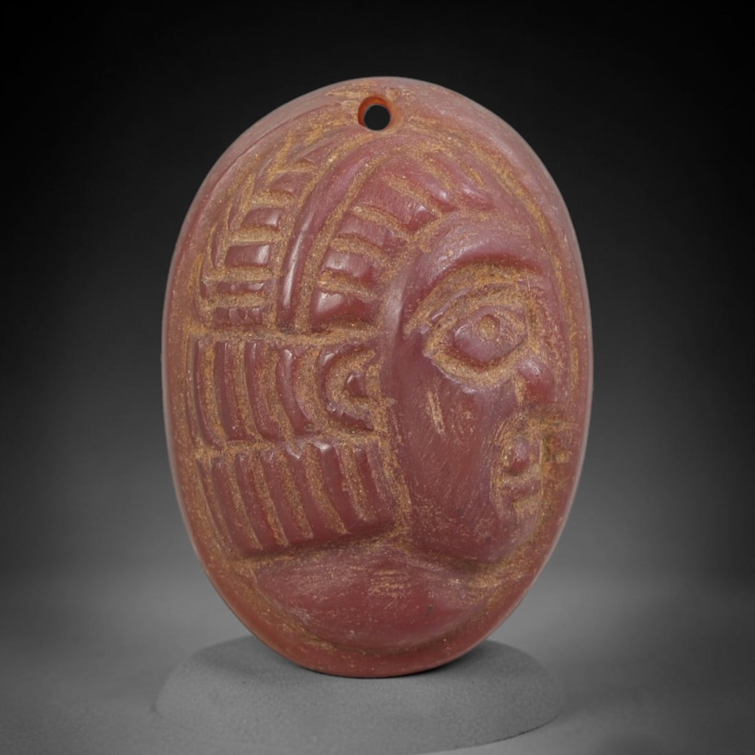 Ancient Carnelian Amulet - Near Eastern Bust Pendant, 60FY: Carved from carnelian, the amulet is an oval disc with a drilled suspension hole at the top, crafted in the ancient Near Eastern style. The front surface bears a raised relief portrait of a human bust