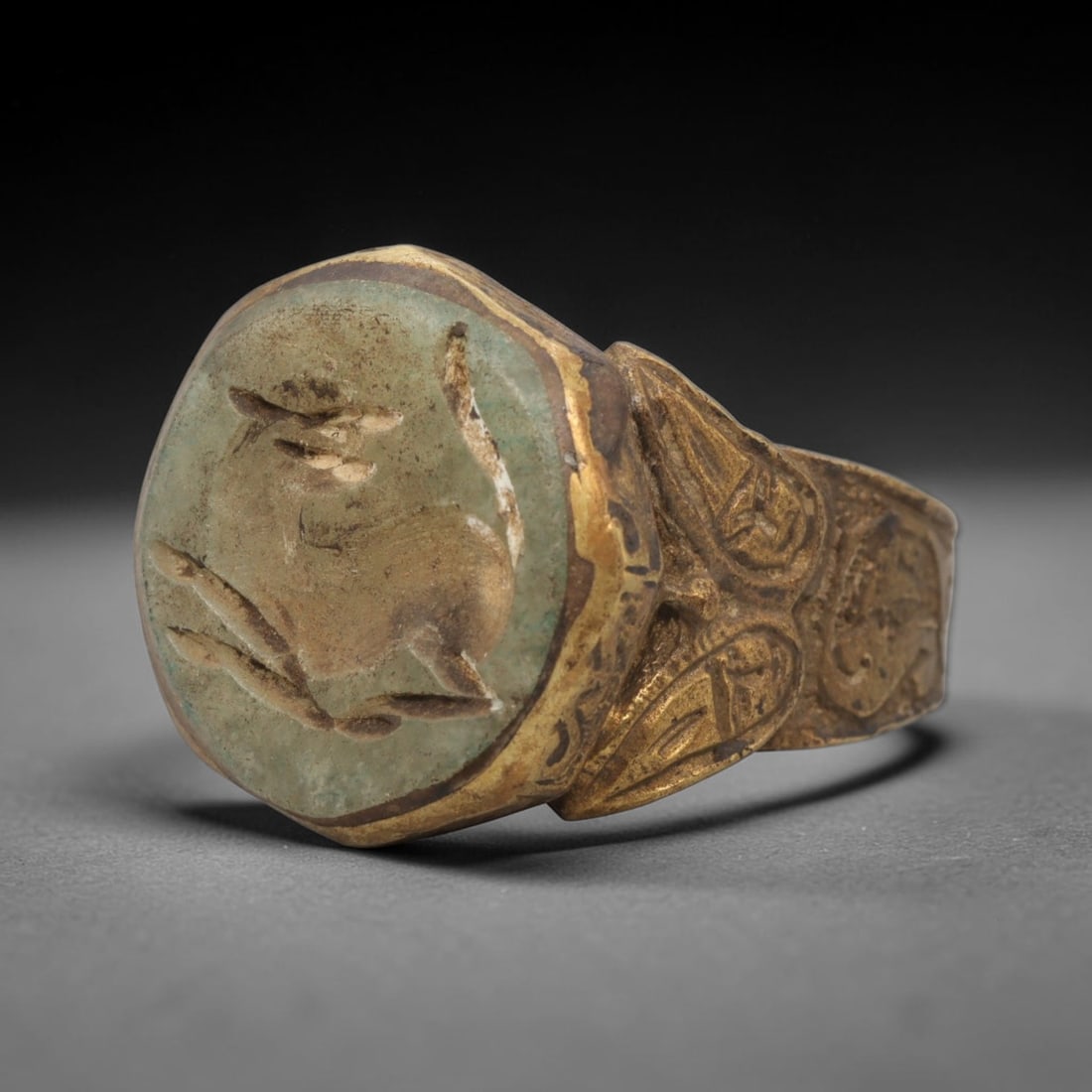 Antique Qajar Dynasty Faience Intaglio Ring - Size 9 US, 84ZX: Crafted from gilt brass with a faceted bezel, this ring features a carved faience intaglio stone at its center, incised with a stylized quadruped motif characteristic of Qajar-era Persian symbolic car