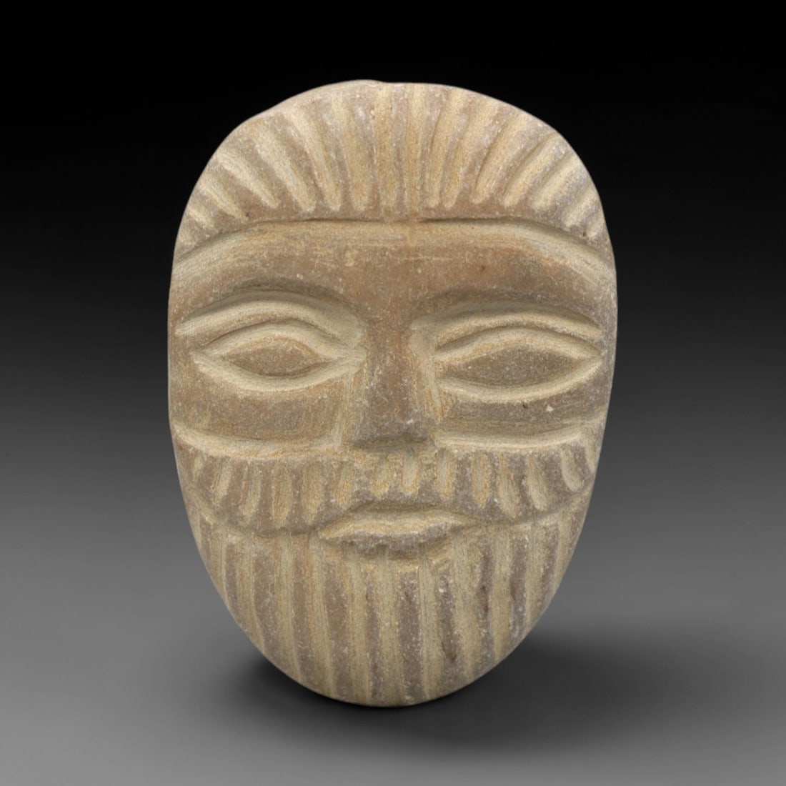 Ancient Stone Face Bead Amulet - Mediterranean / Near Eastern Anthropomorphic Artifact, 18ZR: This artifact is an oval stone face bead amulet, executed in the stylized anthropomorphic tradition of the ancient Mediterranean or Near East. The bead features a serene human face with incised almond