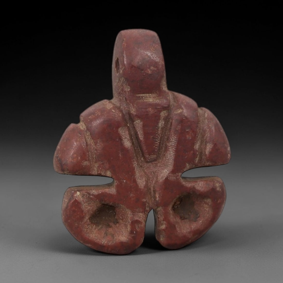 Ancient Stone Tyet Amulet - Egyptian Carved Pendant, 67AG: This amulet is carved from a rich reddish stone with a granular texture and weathered, earthy patina. The form is a stylized Tyet (Knot of Isis) amulet, featuring a rectangular upper suspension segmen