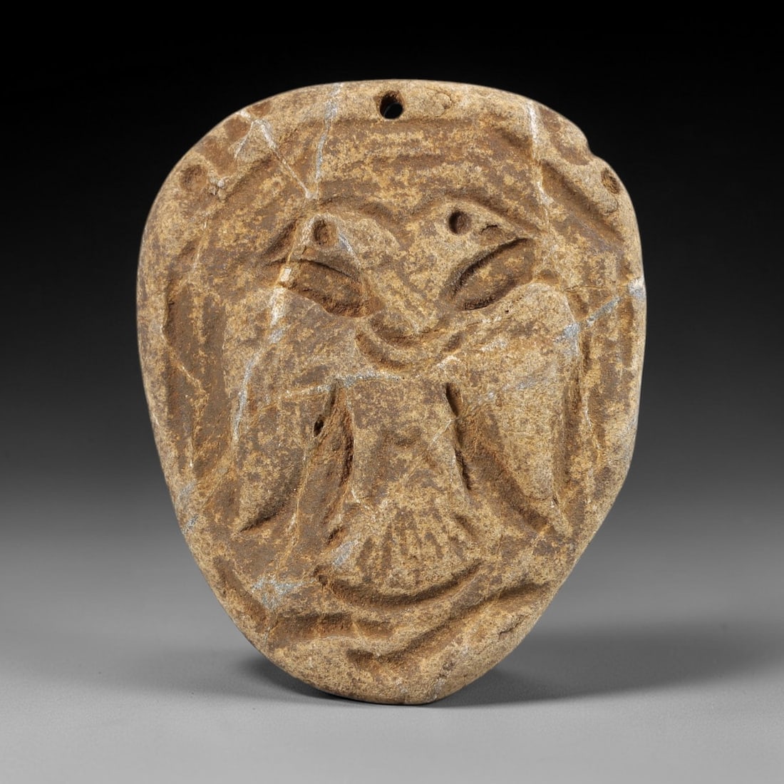 Ancient Stone Double-Headed Bird Amulet - Near Eastern Figurine, 3FY: Carved from a weathered stone, this amulet features a relief depiction of a double-headed bird, with incised details defining its wings, bodies, and facial features, including a primary suspension hol
