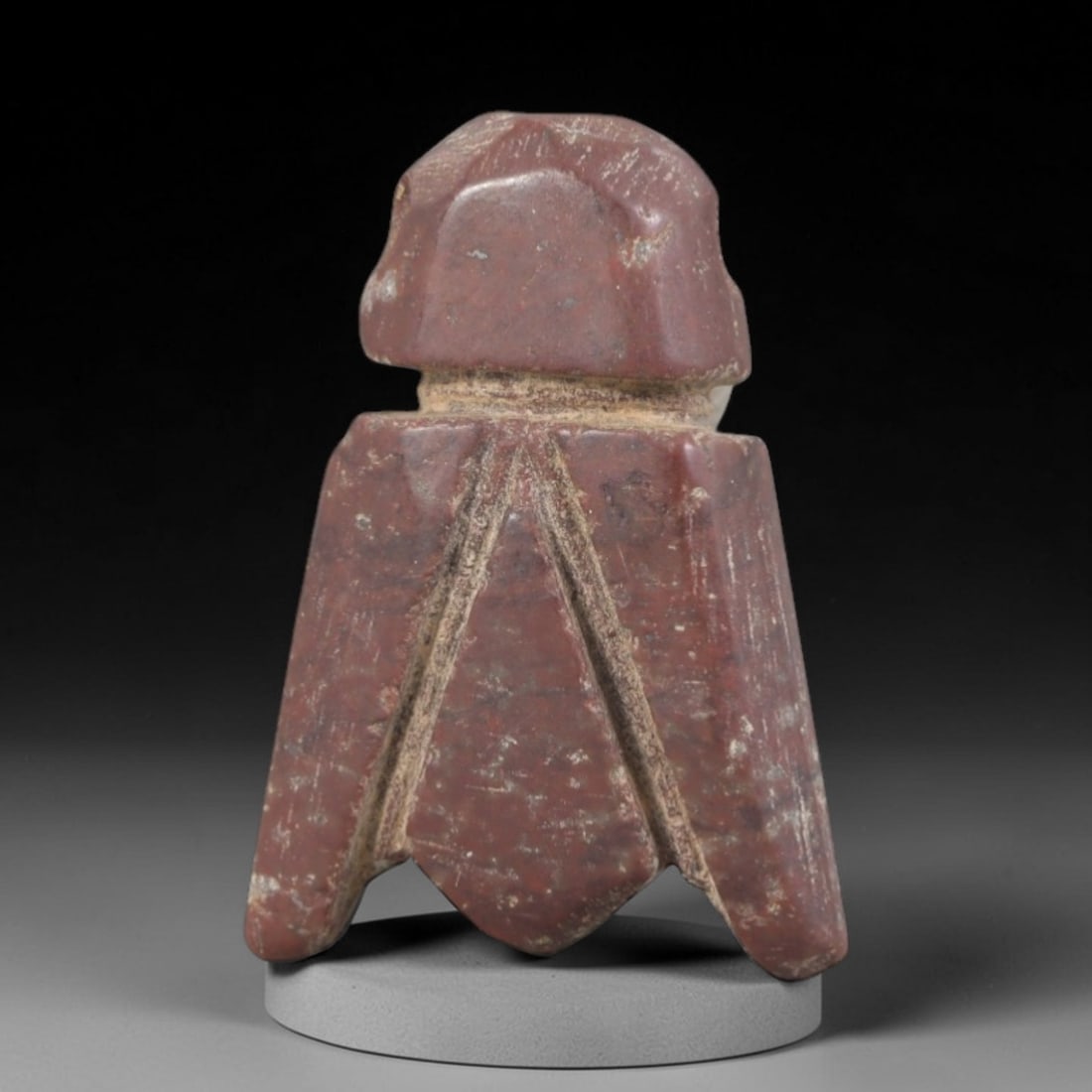 Ancient Stone Fly Amulet - Egyptian Insect Figurine, 87AP: Carved from a dense, reddish stone with natural mineral inclusions and weathered patina, this amulet depicts a stylized fly form with a compact, angular head and broad, segmented wing extensions taper