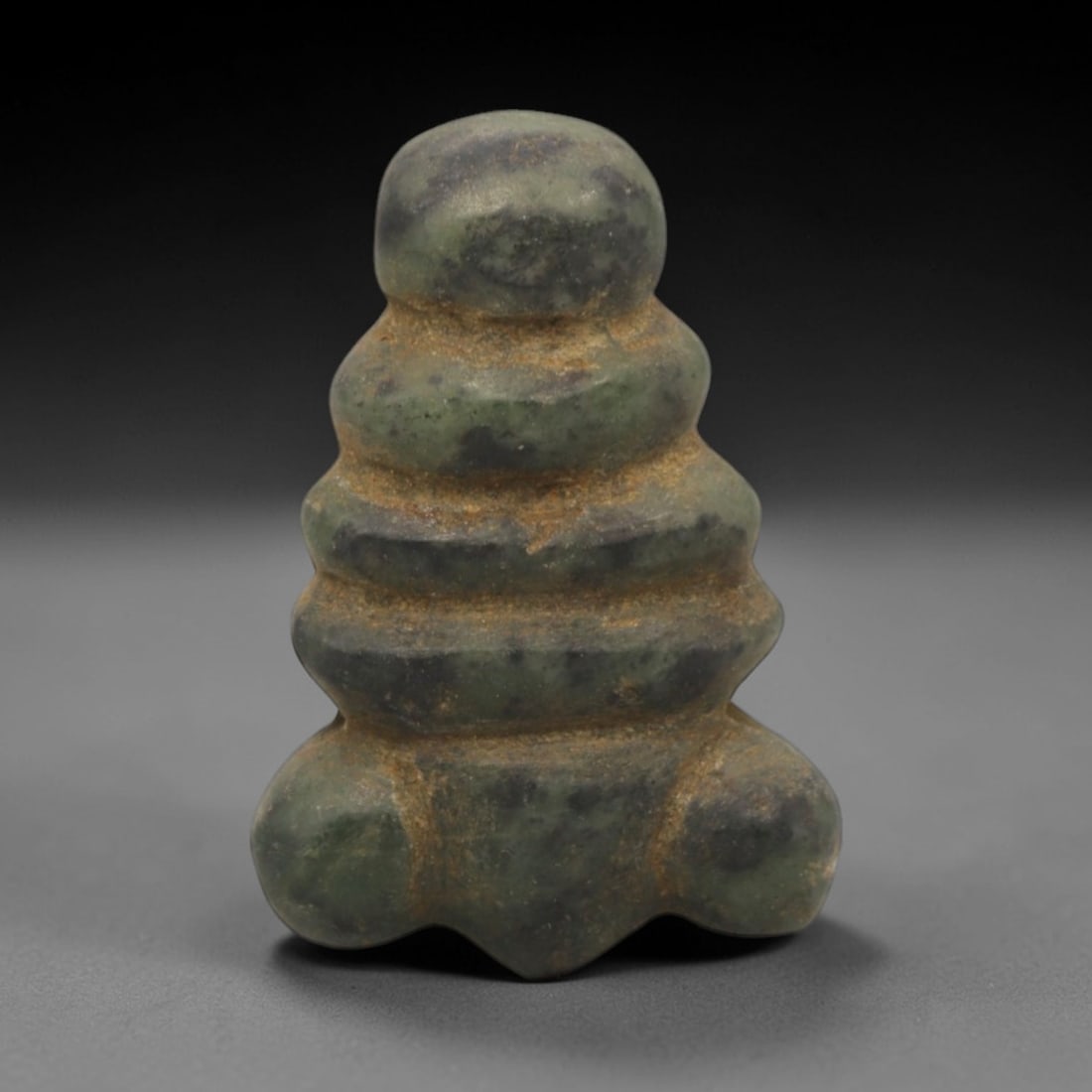 Ancient Stone Stacked Amulet - Near Eastern Figurine, 18XR: Carved from a mottled green stone, this amulet exhibits a stacked, tiered form with a rounded upper terminal and broad, lobed base. The surface displays natural patination and earthy encrustations con