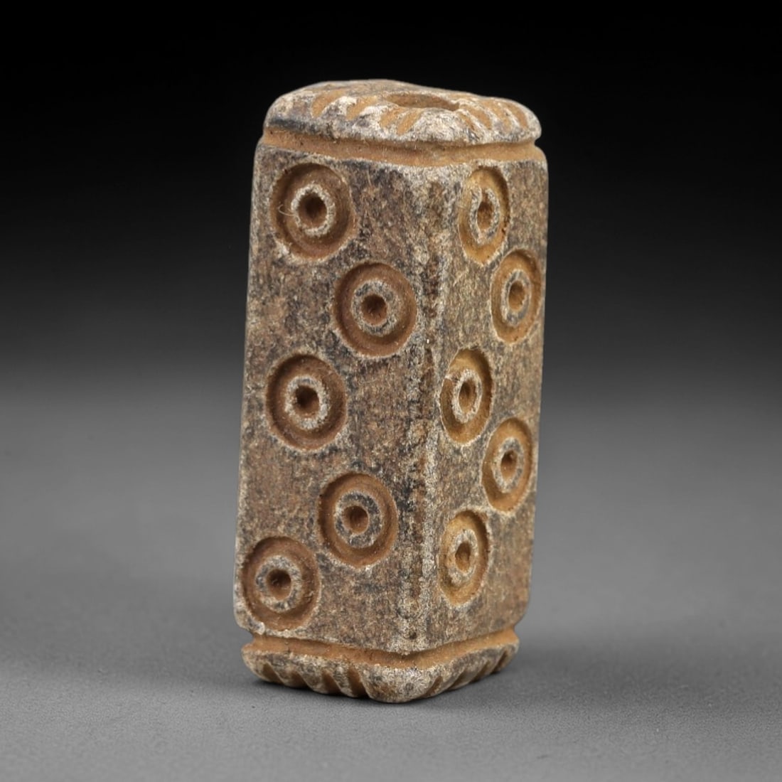 Ancient Steatite Amulet - Near Eastern Concentric Circles, 42AK: Crafted from steatite, this tall rectangular prism amulet features incised concentric circle motifs arranged in vertical rows across its visible faces, with a suspension hole piercing the top rim for