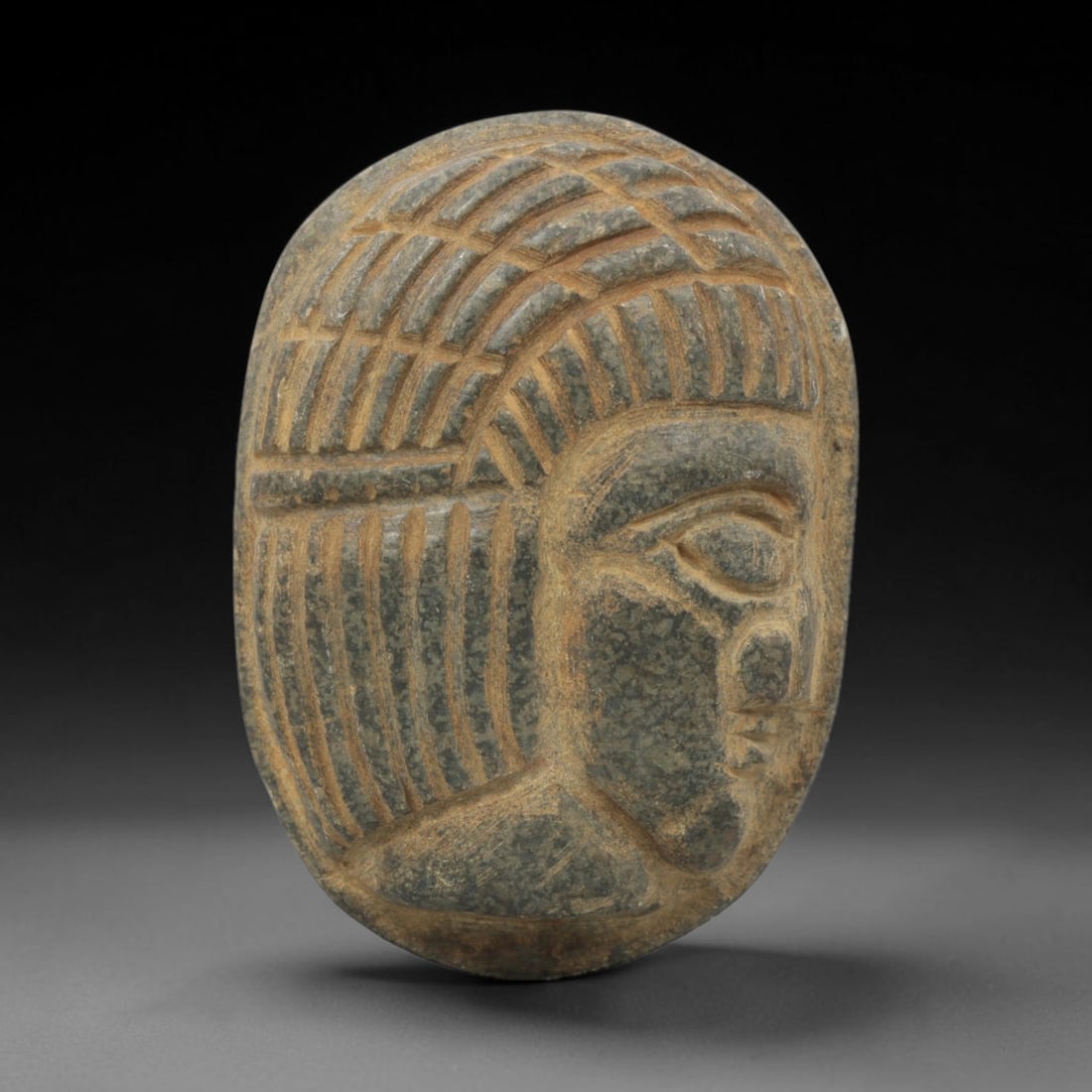 Ancient Stone Amulet - Near Eastern Bust Plaque Pendant, 27ZX: Carved from dark stone, the amulet is an oval plaque crafted in the ancient Near Eastern style, featuring a raised relief portrait of a human bust in profile. The surface bears incised details renderi