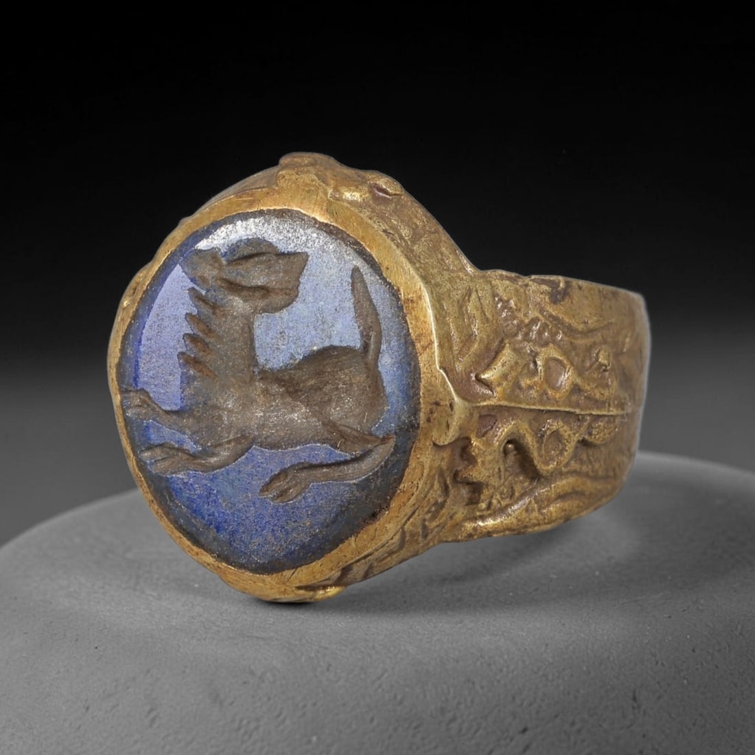 Antique Qajar Dynasty Lapis Lazuli Griffin Intaglio Ring - Size 10 US, 93FY: Crafted from gilt brass with a substantial bezel, this ring features a carved lapis lazuli intaglio stone at its center, incised with a detailed griffin (mythical winged lion) motif-an ancient amuleti
