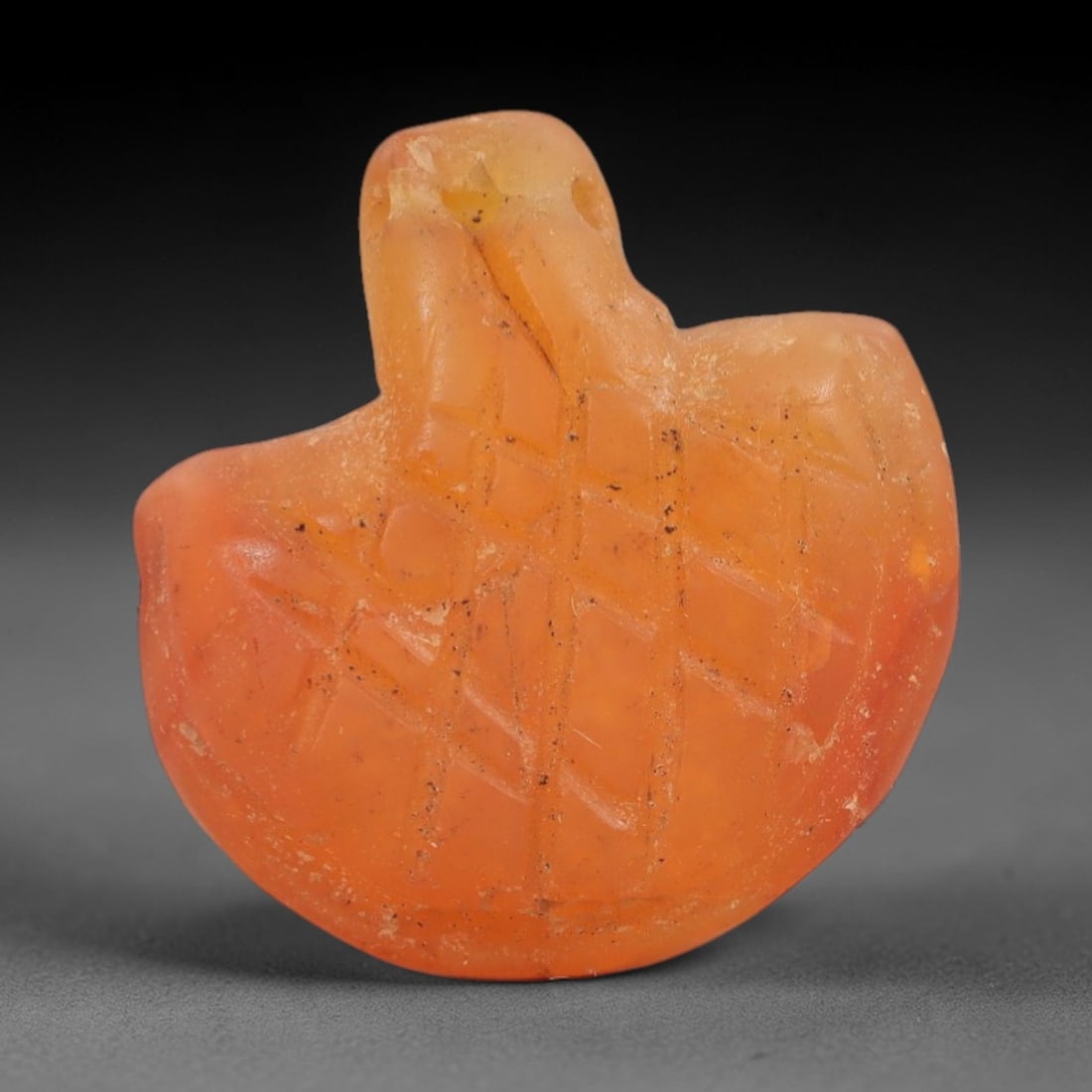Ancient Carnelian Bird Amulet - Near Eastern Figurine, 76AJ: Carved from warm orange carnelian, this amulet is formed as a stylized bird with outstretched wings, featuring incised cross-hatching across the body to denote feather or scale patterns. A suspension