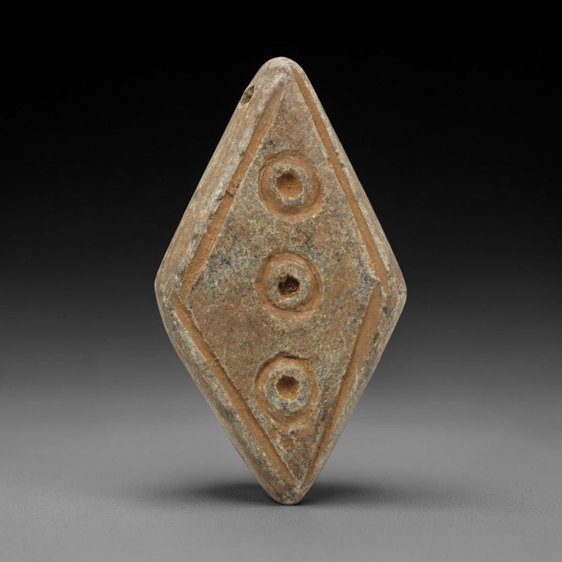 Ancient Schist Amulet - Near Eastern Carved Pendant, 54ZX: Carved from schist, the amulet takes the form of a flattened diamond shape, with a small suspension hole drilled through the upper apex for wear. The central field is decorated with three vertically a