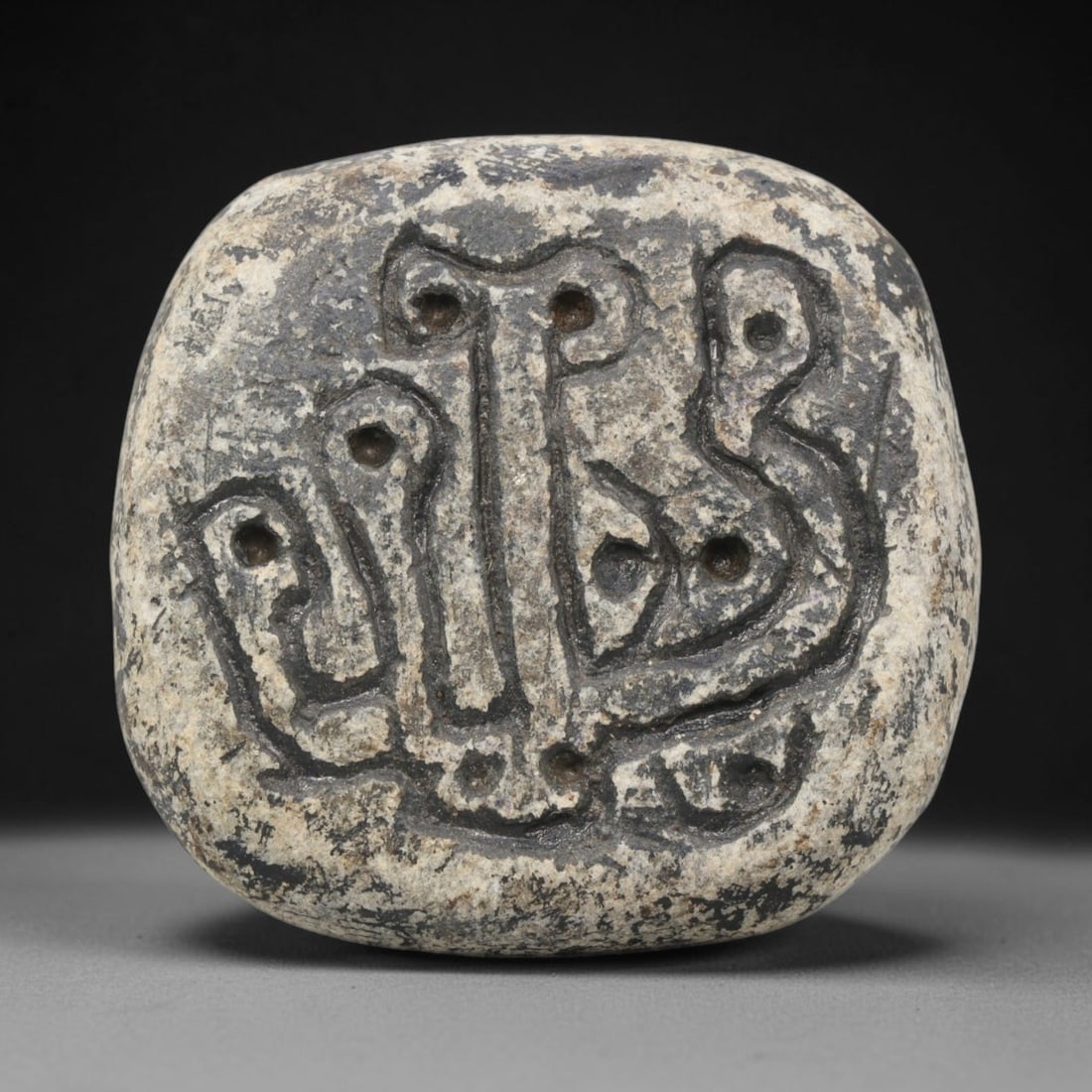Ancient Stone Stamp Seal - Near Eastern Amulet, 26WJ: Carved from stone, this ancient stamp seal features a deeply incised abstract motif with distinct circular and linear elements forming a stylized emblem. The seal's form is rounded with a smooth, weat