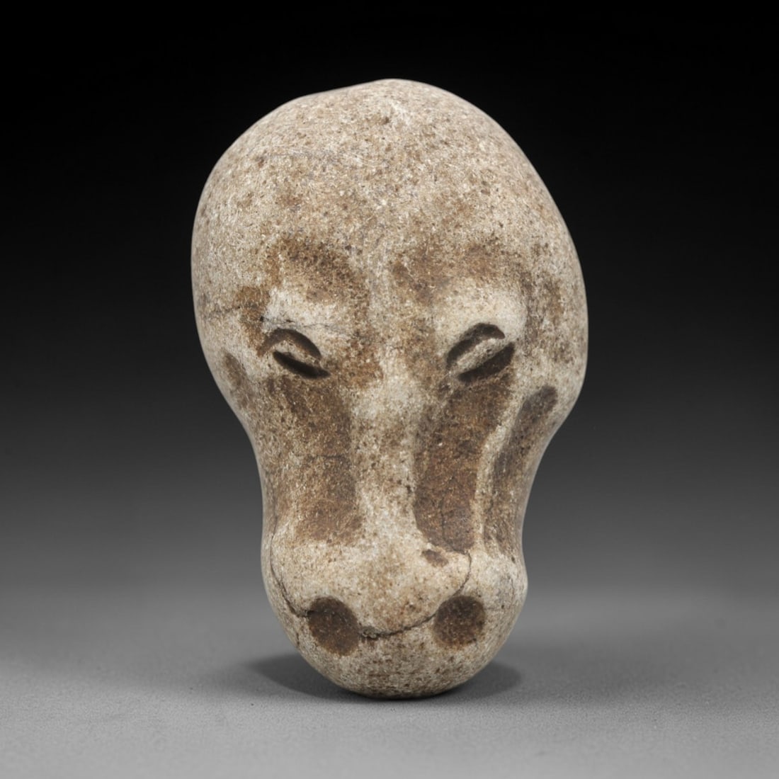 Ancient Stone Zoomorphic Head - Near Eastern Animal Carving, 70ZV: This artifact is a carved stone zoomorphic head, crafted from a light-toned, granular stone consistent with ancient Near Eastern lithic traditions. The relief carving depicts a stylized animal head, l
