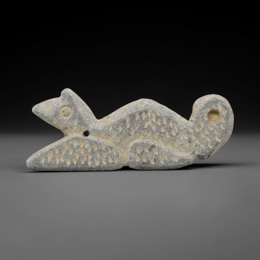 Ancient Stone Rodent Amulet - Near Eastern Zoomorphic Figurine, 30WJ: Carved from a dense, grey-hued stone, this artifact takes the form of a stylized zoomorphic rodent figure, rendered in a recumbent posture. The creature is depicted with a streamlined body, a rounded