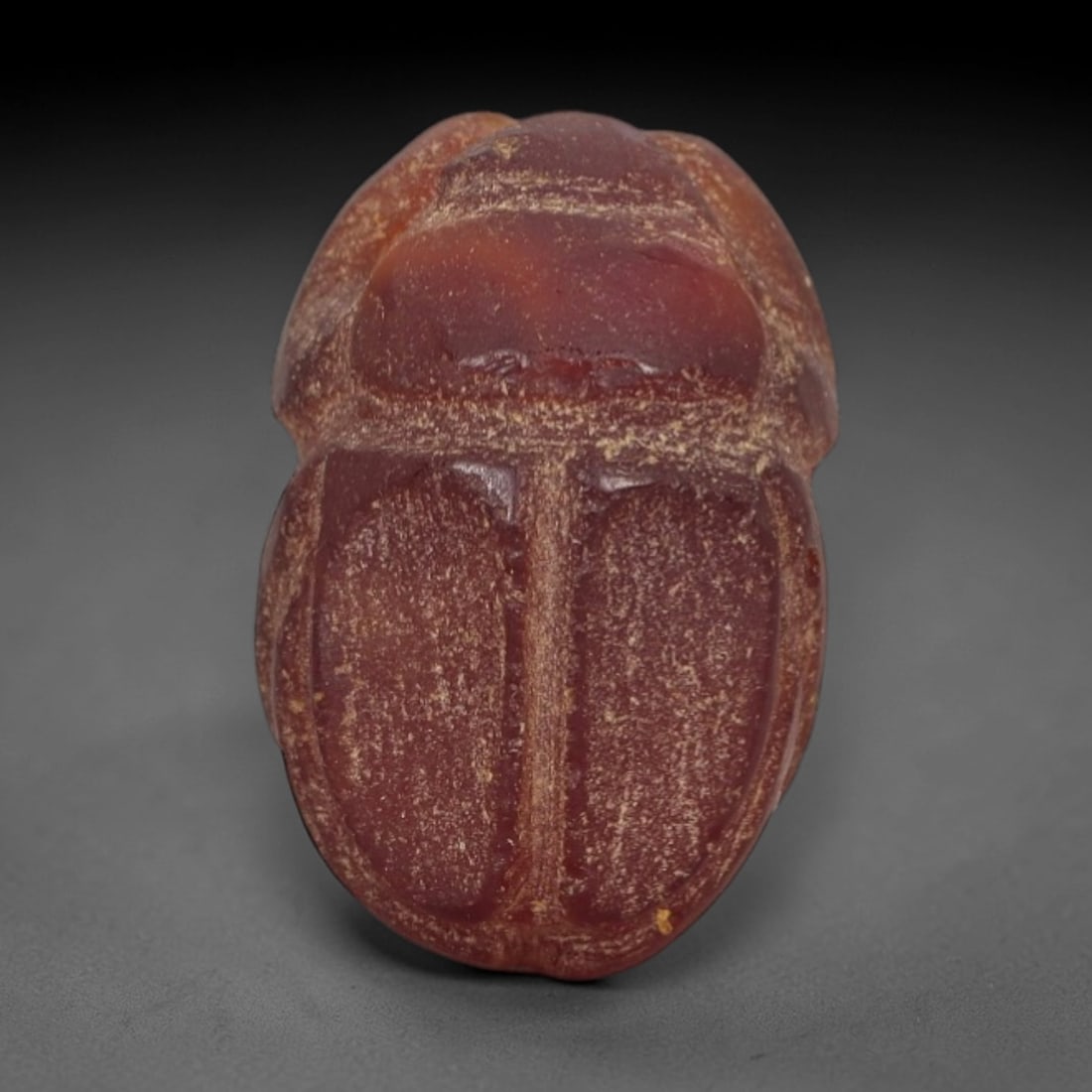 Ancient Red Jasper Scarab Amulet - Egyptian Figurine, 21AJ: Carved from deep, saturated red jasper, this amulet is formed as a stylized scarab beetle with incised linear detailing to define segmented body plates and distinct wing case contours, consistent with