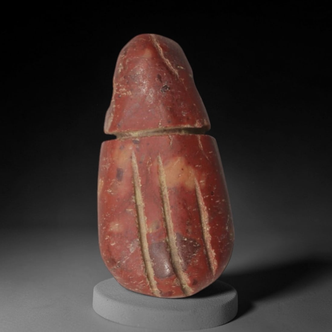 Ancient Red Stone Carved Figurine Amulet, 63XP: Carved from dense, reddish-brown stone with natural banded textures, this miniature zoomorphic-amuletic pendant depicts a stylized humanoid figure, a classic motif in ancient Near Eastern or East Asia