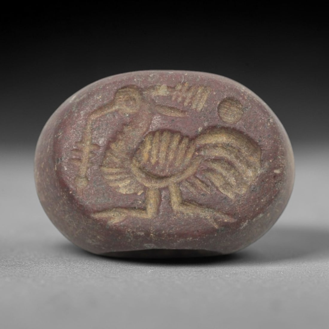 Ancient Stone Hemispherical Stamp Seal - Near Eastern Bird Figure, 83ZS: Crafted from dense, reddish-brown stone, this hemispherical stamp seal bears incised carving of a stylized bird figure, likely a heron or ibis, with a long curved beak, segmented feathered body detail