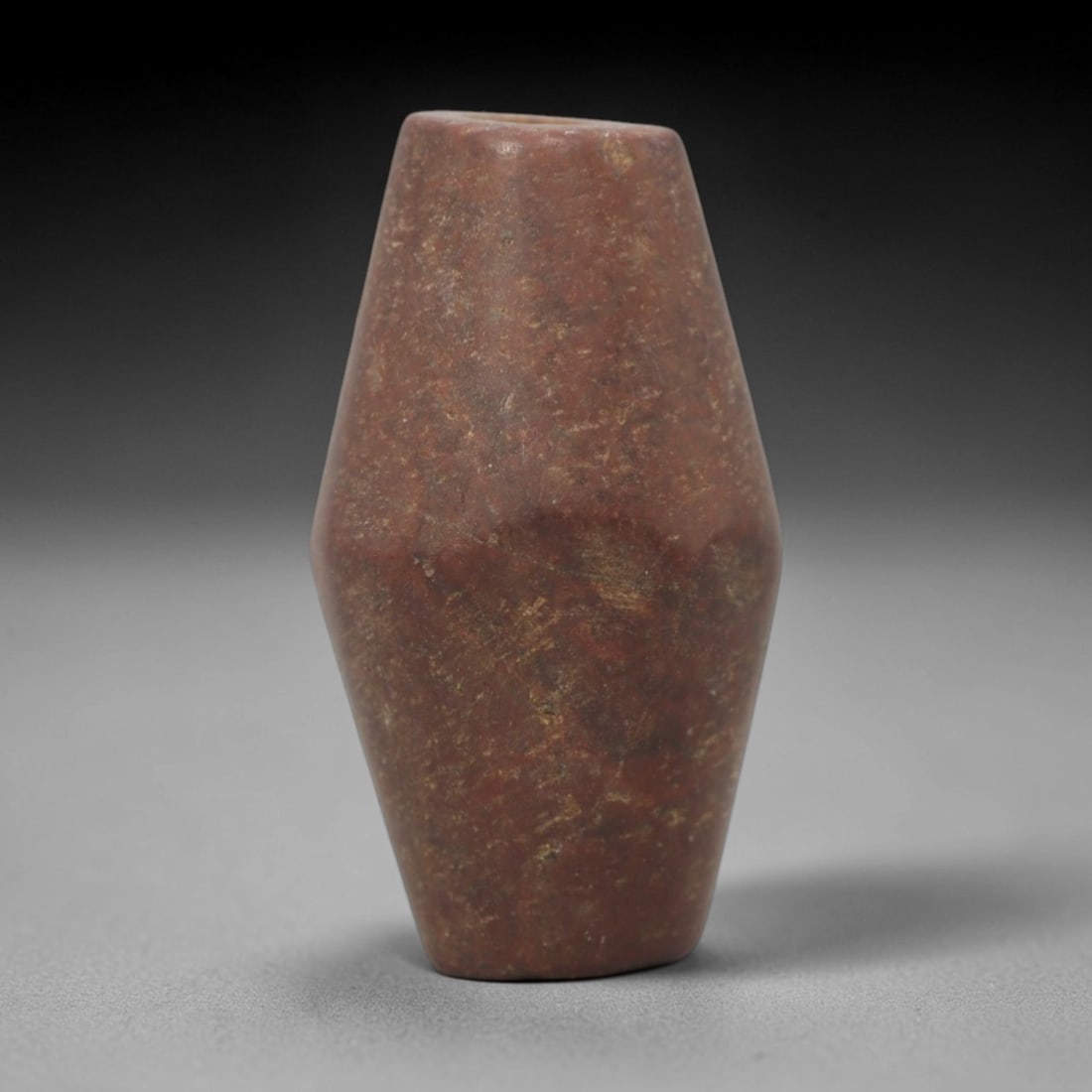 Ancient Near Eastern Red Stone Biconical Bead Amulet - Carved Bead Figure, 41ZV: This amulet is carved from a rich, deep red stone with natural mineral speckling and veining, likely brecciated jasper or red steatite, featuring a classic biconical (double-conical) bead form. The pi