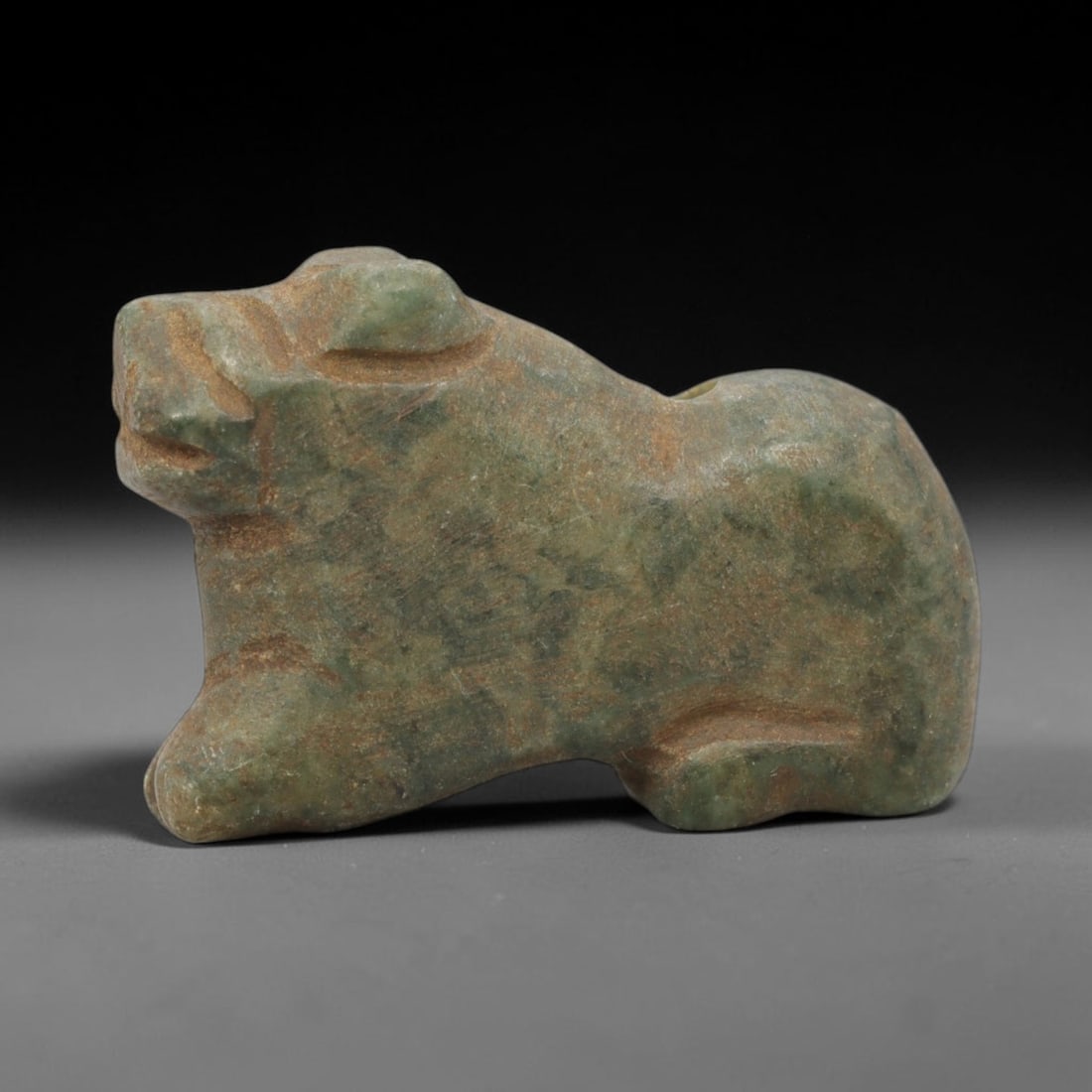 Ancient Serpentine Feline - Near Eastern Amulet Figurine, 19WJ: Carved from serpentine, this ancient Near Eastern amulet takes the form of a stylized feline, rendered with simplified yet distinct incised carvings that define the creature's facial features, body, a